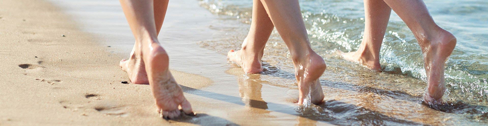 Closeup of Feet of 3 People Walking on Beach